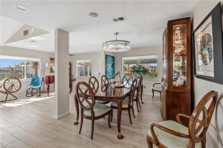 Dining area with light hardwood / wood-style floors and a chandelier /  virtually enhanced photo
