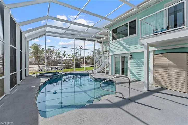 View of pool with a patio area, glass  enclosure, and an in ground hot tub VIRTUALLY ENHANCED