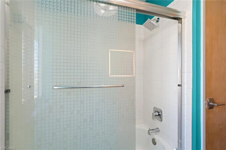 Bathroom with shower / bath combination with glass door /  virtually enhanced photo