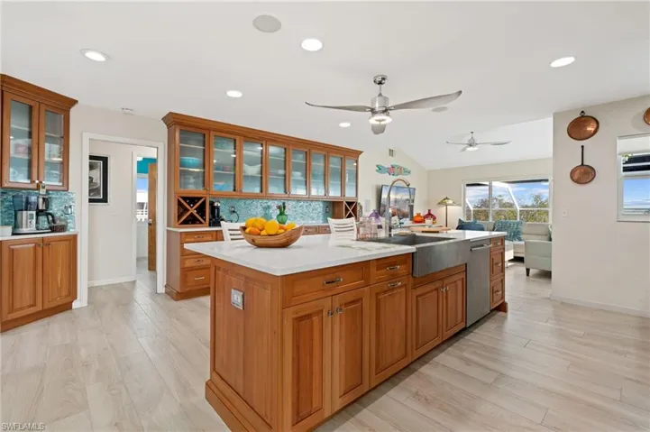 Kitchen featuring a kitchen island with sink, stainless steel dishwasher, light hardwood / wood-style floors, and decorative backsplash / virtually enhanced