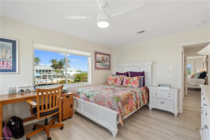 Bedroom with ceiling fan and light hardwood / wood-style floors /  virtually enhanced photo