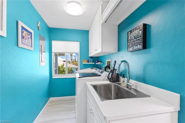 Laundry area with cabinets, sink, light hardwood / wood-style flooring, and washing machine and clothes dryer /  virtually enhanced photo