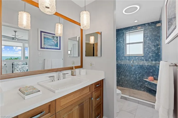 Bathroom with vanity, ceiling fan, a shower with door, and toilet /  virtually enhanced photo