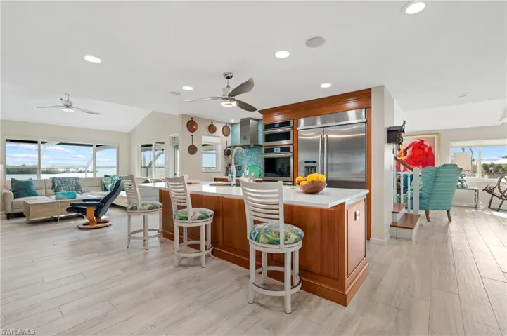 Kitchen featuring a center island with sink, appliances with stainless steel finishes, a breakfast bar area, and light wood-type flooring / virtually enhanced