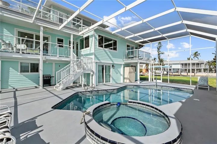 View of swimming pool featuring a lanai, a patio area, and an in ground hot tub VIRTUALLY ENHANCED