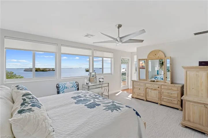 Carpeted bedroom featuring ceiling fan and a water view / virtually enhanced