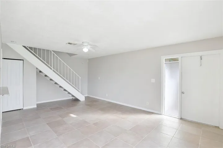 Unfurnished living room with ceiling fan and light tile patterned floors