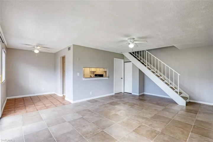 Unfurnished living room featuring a textured ceiling, ceiling fan, and light tile patterned floors
