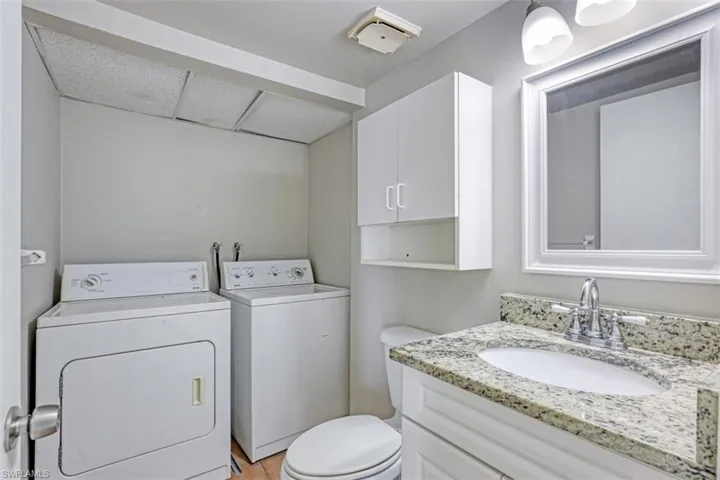 Bathroom featuring toilet, washing machine and clothes dryer, tile patterned floors, and vanity