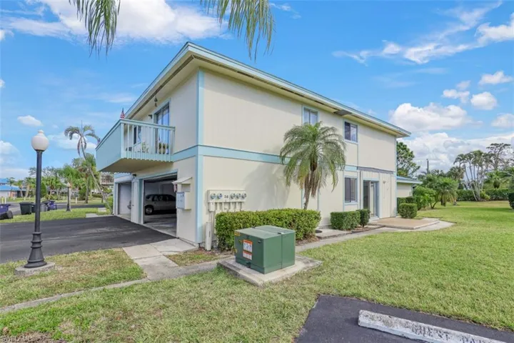View of property exterior with a lawn, a balcony, and a garage