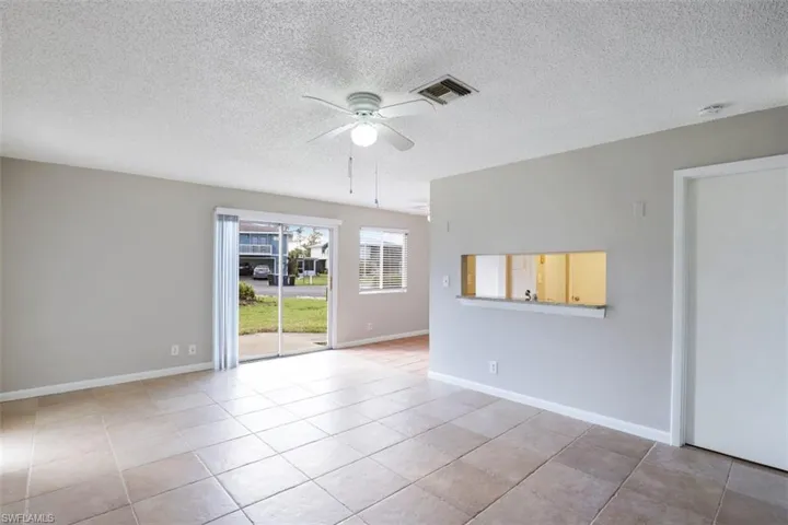 Tiled empty room with ceiling fan and a textured ceiling