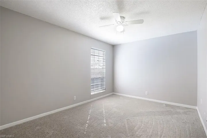 Spare room featuring a textured ceiling, carpet floors, and ceiling fan