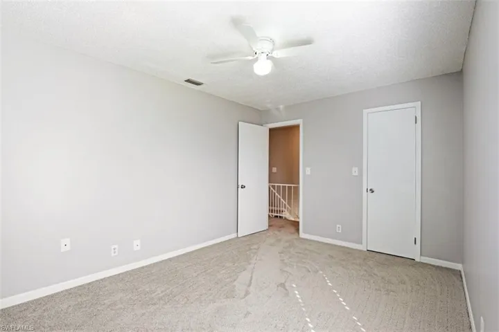 Unfurnished room with ceiling fan, light colored carpet, and a textured ceiling