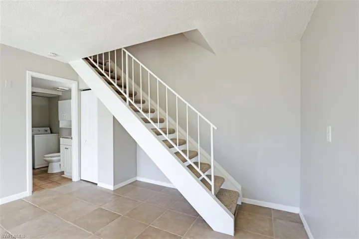 Staircase featuring washer / dryer, tile patterned flooring, and a textured ceiling