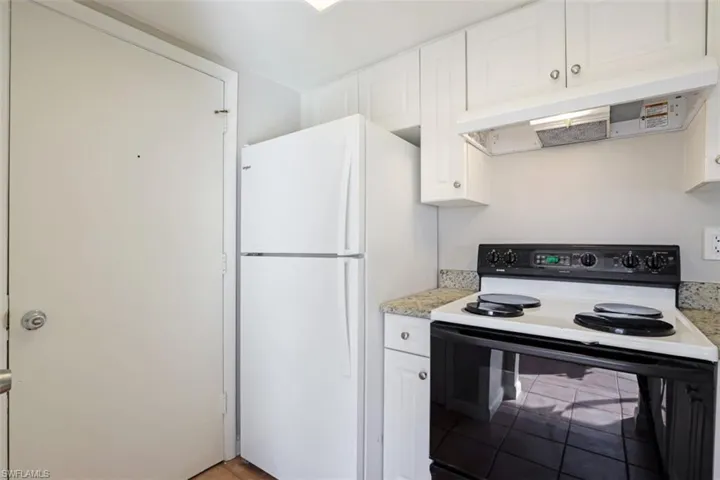 Kitchen with white fridge, white cabinets, and electric range oven