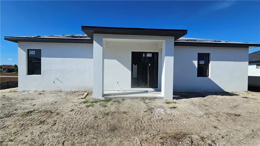Back of house with a metal roof and stucco siding
