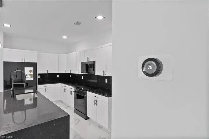 Kitchen featuring a sink, black appliances, marble finish floor, white cabinets, and visible vents