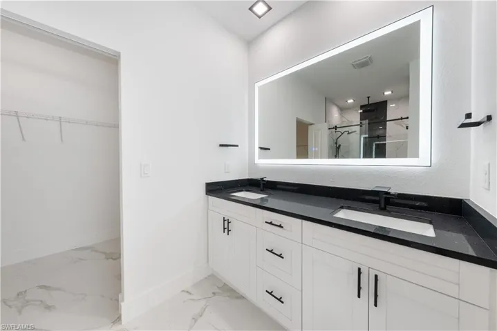 Bathroom with visible vents, marble finish floor, a sink, and a marble finish shower