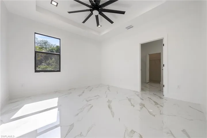 Empty room featuring visible vents, a tray ceiling, baseboards, and a ceiling fan