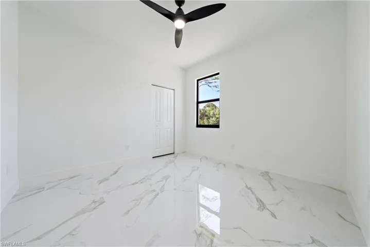 Empty room featuring ceiling fan, marble finish floor, and baseboards