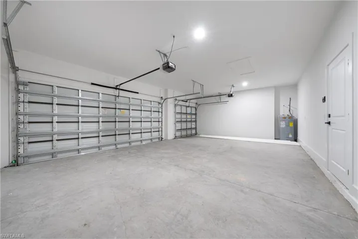 Garage featuring electric water heater, recessed lighting, and a garage door opener