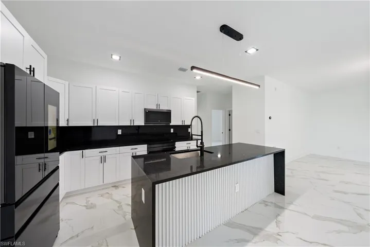 Kitchen featuring white cabinetry, visible vents, black refrigerator with ice dispenser, marble finish floor, and a sink