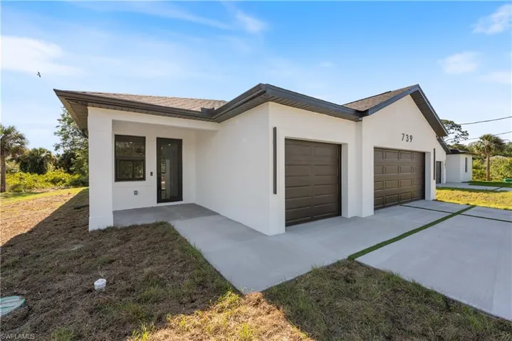 View of front of home with an attached garage, driveway, and stucco siding