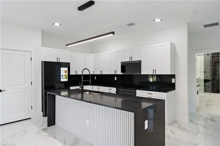 Kitchen with visible vents, a sink, black appliances, and decorative backsplash