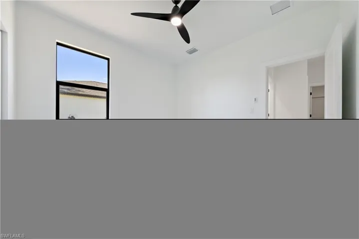 Unfurnished room with visible vents, ceiling fan, and baseboards