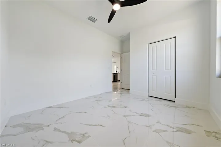 Unfurnished bedroom with visible vents, baseboards, a ceiling fan, and marble finish floor