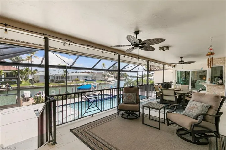 View of patio with a lanai, a sunroom, a pool with connected hot tub, a water view, and a residential view