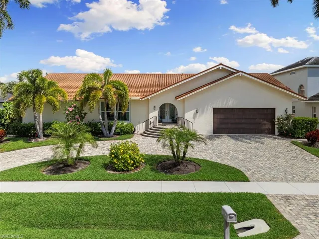 Mediterranean / spanish-style home featuring french doors, curved driveway, an attached garage, stucco siding, and a front lawn