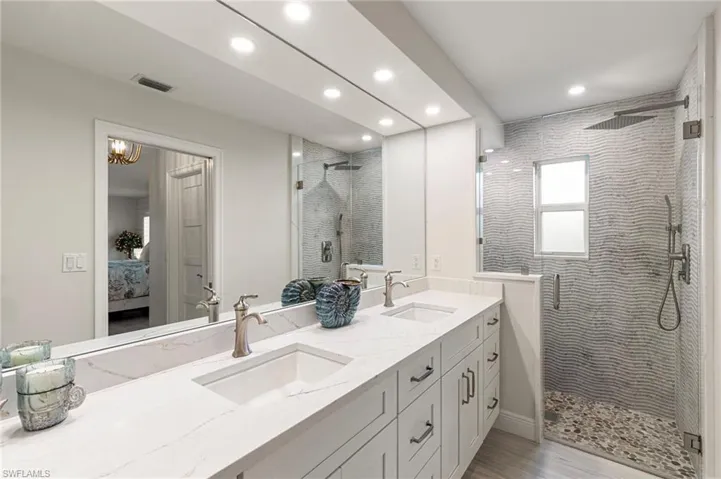 Bathroom featuring connected bathroom, double vanity, a shower stall, and recessed lighting