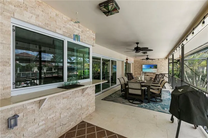 Sunroom with ceiling fan, stone tile flooring, and outdoor dining space