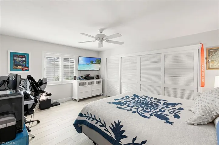 Bedroom with a closet, light wood-style floors, ceiling fan, and an office area