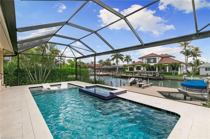 Integrated pool / spa featuring a water view, a sunroom, a lanai, a dock, and boat lift