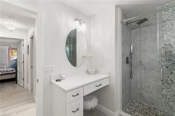 Bathroom featuring a shower stall, connected bathroom, vanity, and light wood-style floors
