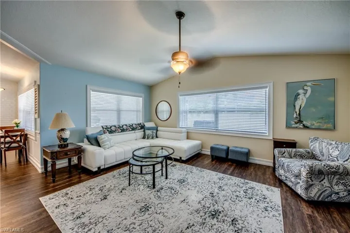 Living room featuring lofted ceiling, ceiling fan, and dark hardwood / wood-style flooring