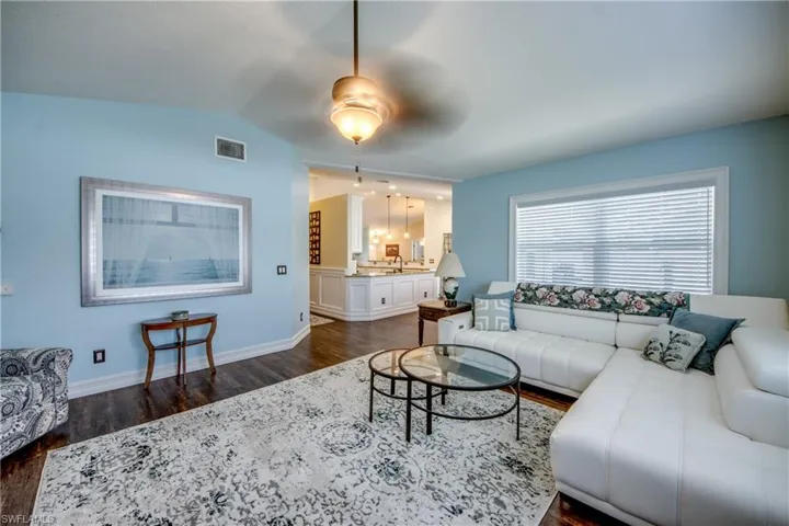 Living room with ceiling fan, dark hardwood / wood-style flooring, lofted ceiling, and sink