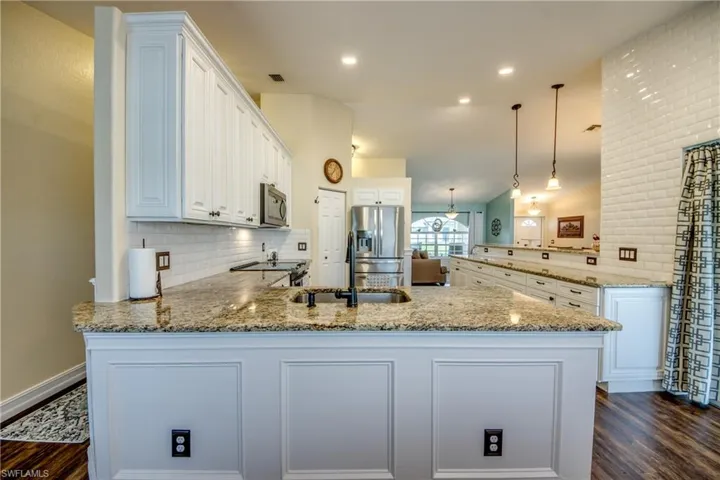 Kitchen with appliances with stainless steel finishes, dark hardwood / wood-style flooring, and kitchen peninsula
