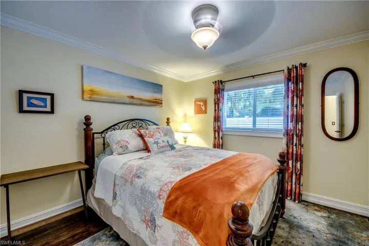 Bedroom with ceiling fan, dark hardwood / wood-style floors, and crown molding