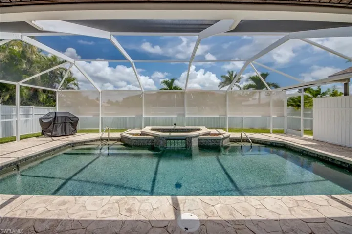 View of swimming pool featuring an in ground hot tub and a lanai