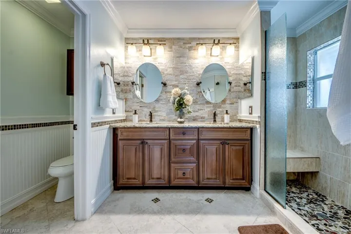 Bathroom with large vanity, tile flooring, ornamental molding, and double sink