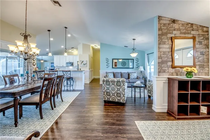 Living room featuring vaulted ceiling, an inviting chandelier, and dark hardwood / wood-style flooring