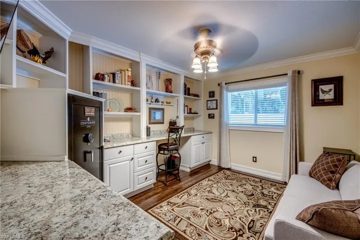 Office area with ornamental molding, hardwood / wood-style flooring, built in features, built in desk, and ceiling fan