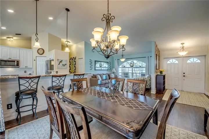 Dining room with dark wood-type flooring, an inviting chandelier, and lofted ceiling