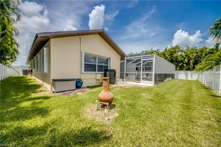 Rear view of property featuring a lanai, a patio area, and a lawn