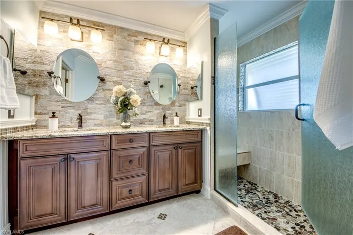 Bathroom with crown molding, oversized vanity, double sink, a shower with door, and tile floors
