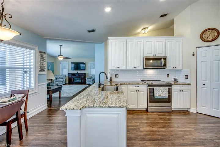 Kitchen featuring lofted ceiling, appliances with stainless steel finishes, dark hardwood / wood-style floors, pendant lighting, and sink