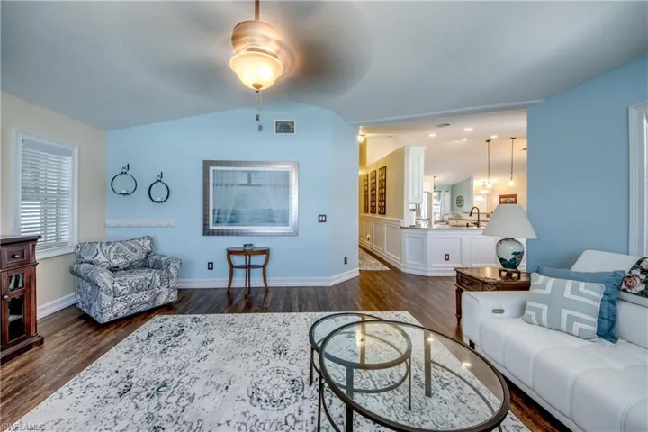 Living room with dark wood-type flooring, sink, ceiling fan, and vaulted ceiling